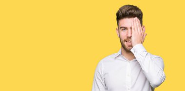 Genç yakışıklı iş adamı yüz ve sürpriz duygu kendinden emin gülümseme ile el ile bir göz kapsayan.