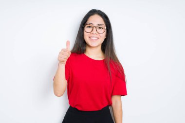 Güzel esmer kadın elle jest kadar mutlu başparmak yapıyor izole arka plan üzerinde gözlük giyiyor. Başarı göstererek kameraya bakan ifadeyi onaylama.