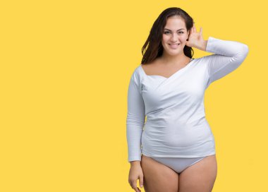 Artı boyutu genç overwight kadın güzel üzerinde beyaz iç çamaşırı giyiyor arka plan bir işitme söylenti ya da dedikodu için dinleme kulak üzerinde el ile gülümseyen izole. Sağırlık kavramı.