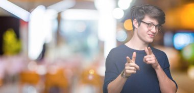 Fotoğraf makinesi ile mutlu ve komik yüz için parmakları işaret izole arka plan üzerinde gözlük takan yakışıklı delikanlı. İyi enerji ve vibes.