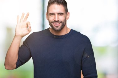 İzole arka plan el ve parmaklar ok işaretiyle yapıyor olumlu gülümseyen üzerinde kazak giyen genç yakışıklı adam. Başarılı ifade.