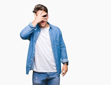Mahcup ifadeyle parmaklarımın arasından seyir yüz ve gözler el ile kapsayan şok bakmak izole arka plan üzerinde güneş gözlüğü takmış genç yakışıklı adam.