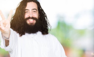 Adam Isa Mesih kostüm gösteren ve parmaklar iki numarası ile işaret giymiş iken emin ve mutlu gülümseyen.