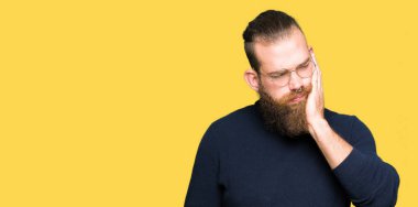 Gözlük ve diş ağrısı veya dişlerde dişlerle ilgili hastalık nedeniyle ağız acı ifadesi ile el ile dokunmak boğazlı kazak giyen genç sarışın adam. Diş hekimi kavramı.