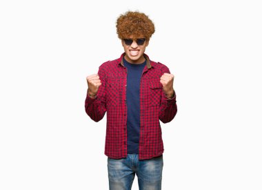 Kutlama güneş gözlüğü takıyor afro saçlı yakışıklı delikanlı şaşırttı ve başarı için kaldırdı Kollarını açarak hayret ve gözleri açık. Kazanan kavramı.