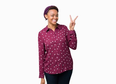 Üzerinde başörtüsü giyen güzel genç Afro-Amerikan kadın arka plan mutlu yüz zafer işareti yaparken kameraya göz kırpıyor ile gülümseyen izole. İki numaralı.
