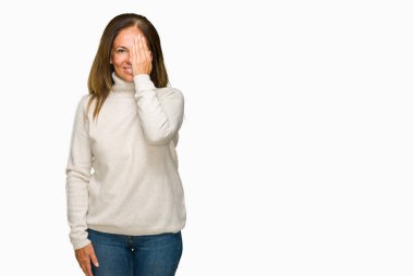 El yüz ve sürpriz duygu kendinden emin gülümseme ile tek gözüyle kapsayan izole arka plan üzerinde kış kazak giyen güzel orta yaş yetişkin kadın.