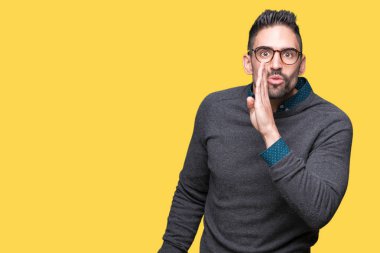 Genç yakışıklı adam gözlük izole arka plan üzerinde kötü amaçlı konuşma konuşma fısıldayan gizli söylenti söylüyor dudaklarından el