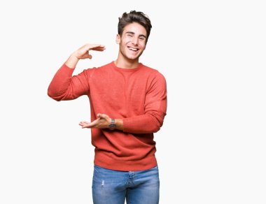 Yakışıklı delikanlı ile büyük ve büyük boy işaret, ölçü birimi sembol gösteren el eller izole arka plan üzerinde. Kameraya bakarak gülümsüyordu. Ölçüm kavramı.