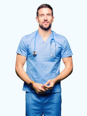Yakışıklı Doktor adam üzerinde tıbbi üniforma birlikte arka plan eller izole ve rahat ve neşeli gülümseyen parmak çarpı işareti. Başarı ve iyimser