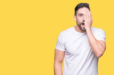 Üzerinde rahat beyaz t-shirt giyen genç adam arka plan kapsayan bir göz yüz ve sürpriz duygu kendinden emin gülümseme ile el ile izole.