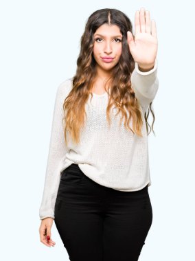 Beyaz kazak giyen genç güzel kadın el avuç ile şarkı durdurmak yapıyor. Yüz üzerinde negatif ve ciddi jest ile uyarı ifadesi.