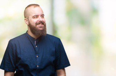 Genç beyaz hipster adam görünümlü yan ve dik dik bakma uzağa düşünce gülümseyen izole arka plan.