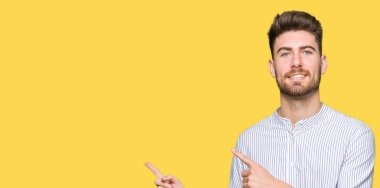 Yakışıklı genç gülümseyen ve iki elleri ve parmakları ile tarafına işaret kamera bakarak adam.