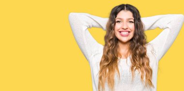 Beyaz kazak giyen genç güzel kadın Rahatlatıcı ve kollar ve eller baş ve boyun arkasında germe, mutlu gülümseyen