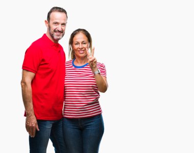 Orta yaş İspanyol çift aşık gösterilen ve parmakları ile işaret izole arka plan üzerinde kendinden emin ve mutlu gülümseyerek iken ikincisi.