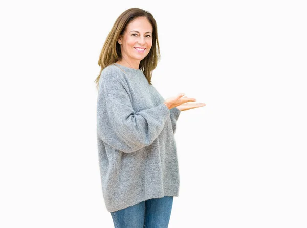 開いた手で自然な笑顔を入力する招待孤立の背景に冬のセーターを着て美しい中年女性 — ストック写真