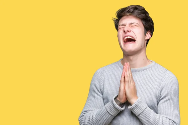 Young handsome man wearing winter sweater over isolated background begging and praying with hands together with hope expression on face very emotional and worried. Asking for forgiveness. Religion concept.