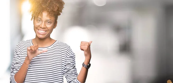 Beautiful young african american woman wearing glasses over isolated background Pointing to the back behind with hand and thumbs up, smiling confident