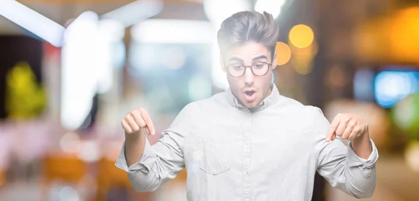 Genç Yakışıklı Adam Gözlük Izole Üzerinde Işaretleme Aşağı Reklam Sürpriz — Stok fotoğraf