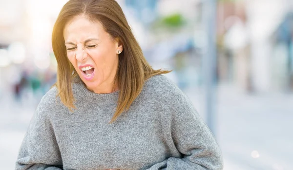 Beautiful middle age woman wearing winter sweater over isolated background with hand on stomach because indigestion, painful illness feeling unwell. Ache concept.