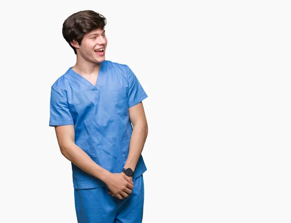 若い医者 自然な表現の顔に笑みを浮かべて側に離れて見て孤立の背景に医療制服を着てします 自信を持って笑ってください — ストック写真