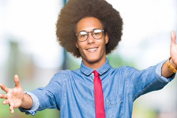 メガネとハグするため両手を広げて笑みを浮かべてカメラを見て赤のネクタイを身に着けているアフロの髪の若いアフリカ系アメリカ人ビジネスマン晴れやかな表情の受け入れ幸せ — ストック写真