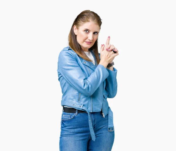 Beautiful middle age mature woman wearing fashion leather jacket over isolated background Holding symbolic gun with hand gesture, playing killing shooting weapons, angry face