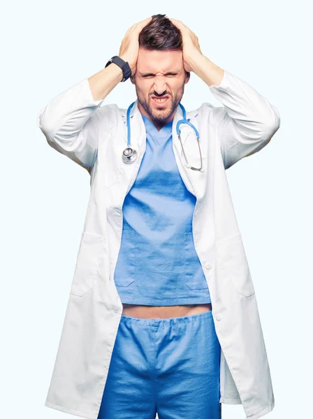 英俊的医生穿医疗制服在孤立的背景下遭受头痛绝望和压力 因为疼痛和偏头痛 双手放在头上 — 图库照片