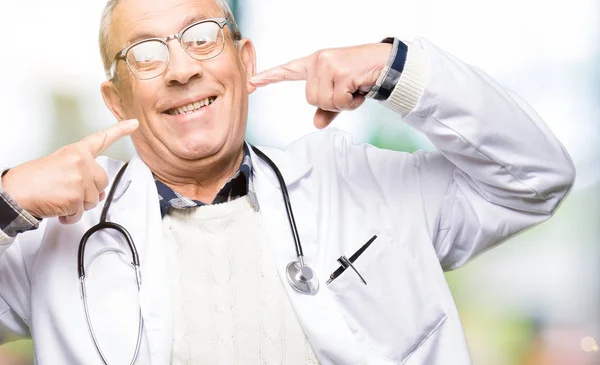 ハンサムな先輩医師男は自信を示すと指歯と口を指して笑って医療のコートを着ています 健康の概念 — ストック写真