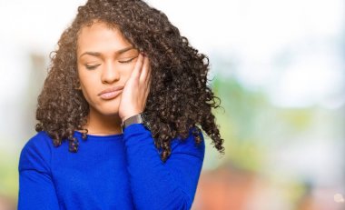 Kıvırcık saçlı kış kazak düşünme seyir giyen genç güzel kadın yorgun ve sıkılmış çapraz silah depresyon sorunları ile.