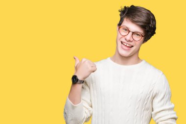 Seyir ve başparmak yanında yukarıyı mutlu yüz ile gülümseyen izole arka plan üzerinde gözlük takan genç yakışıklı adam.