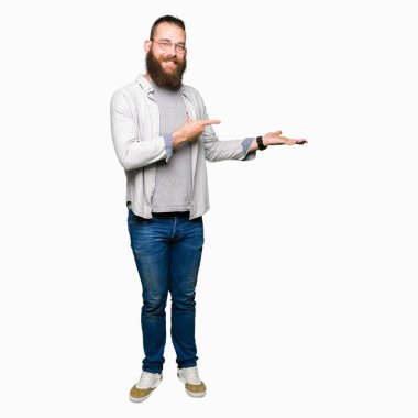 Hayret ve el ile sunulması ve parmak ile işaret ederken kameraya gülümseyen gözlüklü genç sarışın adam.