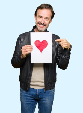 Kağıt kırmızı kalp ile çok mutlu el ve parmak ile işaret tutan yakışıklı orta yaş erkek