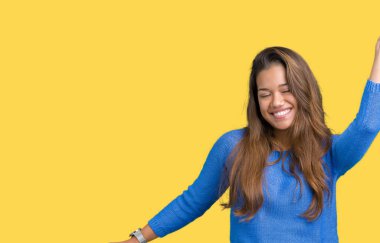 İzole arka plan dans mutlu ve neşeli, hareketli rahat ve kendinden emin müzik gülümseyen üzerinde mavi kazak giyen genç güzel esmer kadın