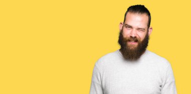 Genç sarışın giyen sıradan kazak göz kırpıyor seksi bir ifadeyle, neşeli ve mutlu yüzünü kameraya bakarak adam.