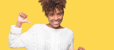 Yüzünde gülümseme ile kendinden emin görünüyorsun, kendini gururlu ve mutlu parmakları ile işaret izole arka plan üzerinde kış kazak giyen güzel genç Afro-Amerikan kadın.