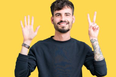 Yakışıklı delikanlı gösterilen ve parmakları ile işaret izole arka plan üzerinde kendinden emin ve mutlu gülümseyerek süre yedi numara.
