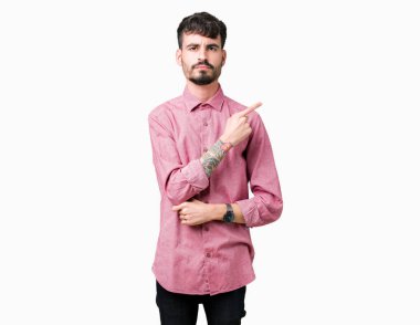 Pembe gömlek izole üzerinde giyen genç yakışıklı adam arka plan işaretçi el parmak tarafı gösteren reklam, ciddi ve sakin yüz için