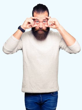 Rahat kazak giyen genç sarışın adam parmaklarıyla gözleri açmaya çalışıyor, uykulu ve yorgun sabah yorgunluğu için