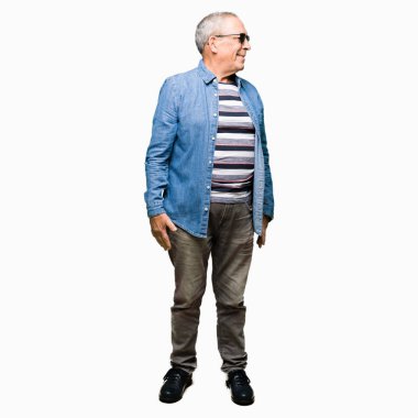 Yakışıklı kıdemli dostum giyen denim ceket ve uzak yan yüzünde, doğal ifade gülümseme ile seyir güneş gözlüğü. Kendine güvenen gülüyor.