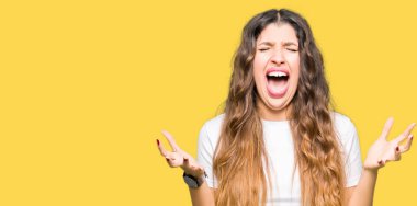 Genç güzel kadın rahat beyaz t-shirt deli giyen ve deli bağırarak ve agresif ifade ve kollar kaldırdı ile bağırıyor. Hayal kırıklığı kavramı.