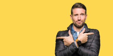 Yakışıklı adam kış ceket giyen her iki parmak ile işaret eden, farklı yönde katılmıyorum