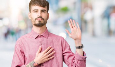 Yakışıklı delikanlı üzerinde pembe gömlek giymiş izole arka plan göğüs ve bir sadakat sözü yemin yapma avuç, el ile küfür