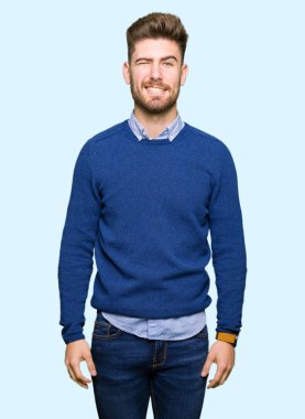 Genç yakışıklı bussines adam seksi bir ifadeyle, neşeli ve mutlu yüzünü kameraya bakarak göz kırpıyor.