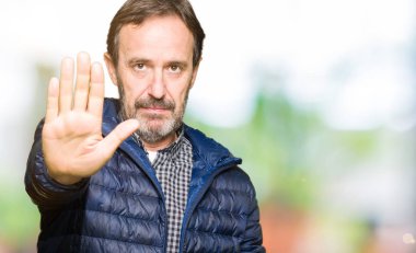 Orta yaş yakışıklı adam elin avuç durağı şarkı yapıyor kış palto giyiyor. Negatif ve ciddi bir jest yüz ifadesiyle uyarı.