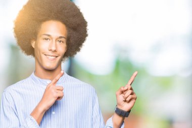 Gülümseyen ve iki elleri ve parmakları ile tarafına işaret kamera bakarak afro saçlı genç Afro-Amerikan adam.