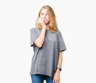 Stresli ve gergin elle çivi ısırma ağzına bakarak izole arka plan üzerinde büyük boy rahat t-shirt giyen güzel ve genç birbayan. Anksiyete sorunu.