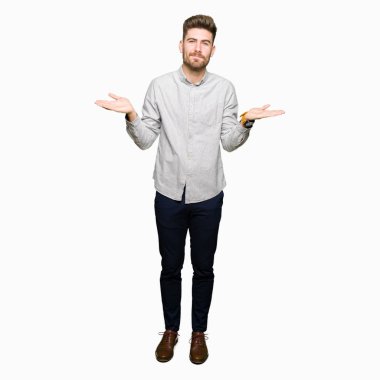 Sıradan gömlekler giyen, elleri ve kolları havada, kafası karışmış genç yakışıklı bir adam. şüphe kavramı.