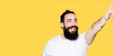 Uzun saç ve sakal casual beyaz t-shirt işaret parmağınızla sürpriz devam et, giyen genç hipster adamla ağız açık ifade, önünde bir şey hayret